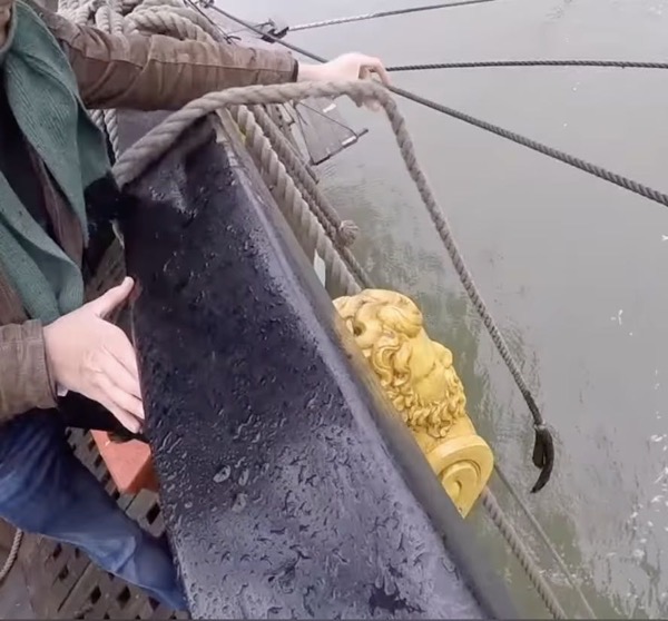 a man on board a ship pulling a tow rag on a rope from the water.